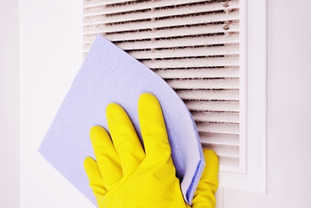 gloved hand cleaning air vent